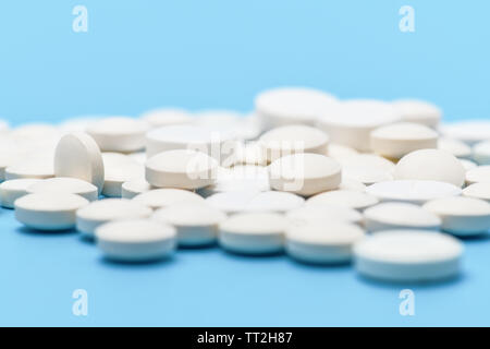 Close-up of lots of white round pills on blue background. Medical background Stock Photo