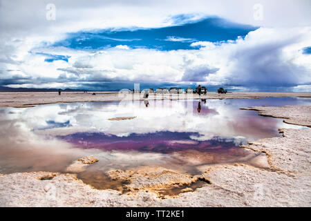 Salar de Uyuni, Bolivia - Dec, 31, 2018: Salar de Uyuni in Bolivia covered with water with car and people reflections Stock Photo