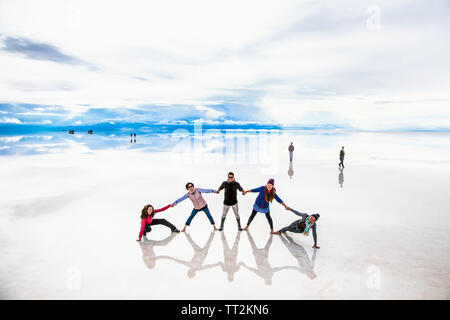 Uyuni, Bolivia- Dec 31, 2018: Group of people make figures with their bodies on the lake Salar de Uyuni, Bolivia. America Stock Photo