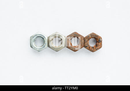 The new and the old rusty nuts on a white background. Metal corrosion. Stock Photo