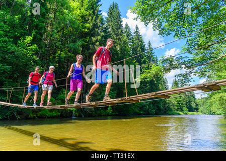 A group of hikers crossing a small footbridge over the Wertach river near the village Wald in the Allgäu Stock Photo