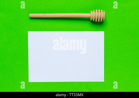 Stick to honey and white sheet of paper on a green background.Horizontal photo. Stock Photo