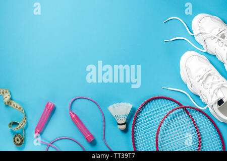 Sport equipment. Shuttlecock and badminton racket, skipping rope, sneakers and measuring tape on blue background. Fitness, sport and healthy lifestyle Stock Photo