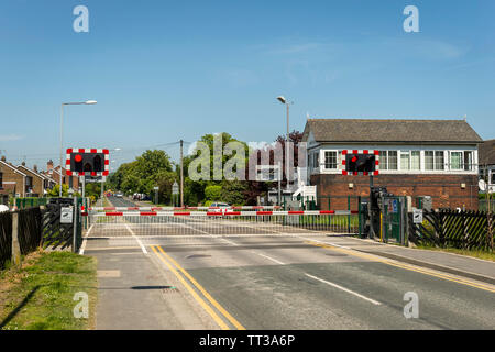 Safety barriers in the closed position across a railway level crossing in the United Kingdom. Stock Photo