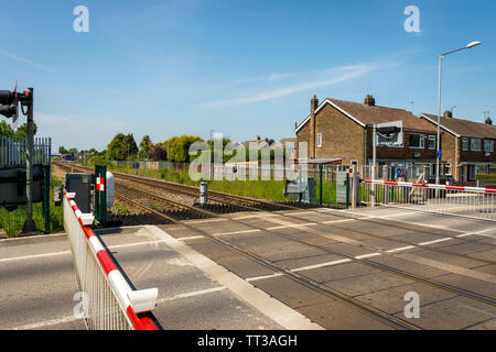 Safety barriers in the closed position across a railway level crossing in the United Kingdom. Stock Photo