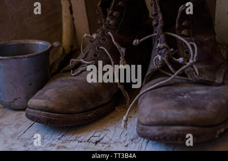 vintage old worn out work boots and a cup Stock Photo