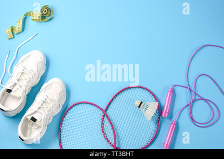 Sport equipment. Shuttlecock and badminton racket, skipping rope, sneakers and measuring tape on blue background. Fitness, sport and healthy lifestyle Stock Photo