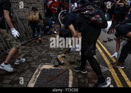 Protesters remove bricks from a road during a protest against extradition bill in Hong Kong, China. Stock Photo