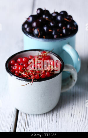 Summer berries in color mugs on color wooden background Stock Photo - Alamy