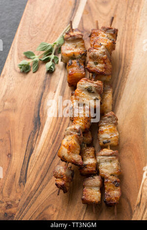 Cubes of cooked Britih belly pork bought from a supermarket that have been marinated in lemon juice and fresh chopped oregano and then skewered on bam Stock Photo