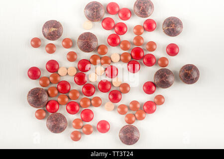 Many red  brown pills on a white background. Different size of sphere drugs splatter on background. Stock Photo