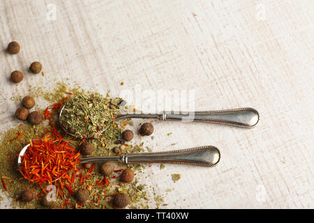 Metal spoons full of different seasoning on white wooden background Stock Photo