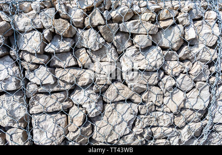 Stone wall with metal grid as background. Rock texture in metal grid Stock Photo