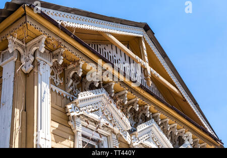 Russian traditional wooden architecture. Facade of an old house decorated with wooden carvings, platbands, wooden lace ornament Stock Photo