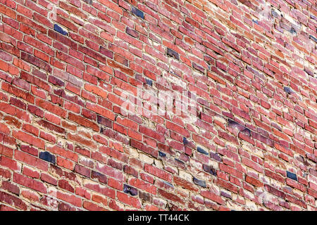 Vintage red brick wall as background texture. Bricks masonry with uneven seams. View from the angle Stock Photo