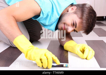 Young man cleaning floor in room Stock Photo