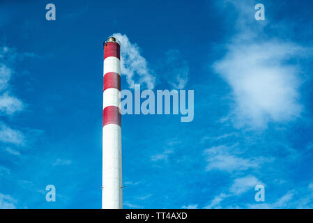 Red and white industrial chimney standing out in the cloudy sky, air pollution Stock Photo