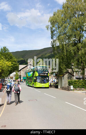 Grasmere, UK: An open-topped bus forming the 599 service between Grasmere and Bowness that's popular with tourists, picks up passengers in Grasmere. Stock Photo