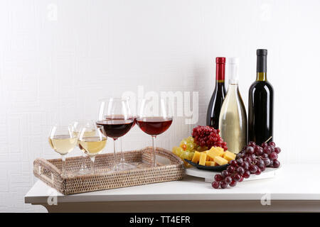 Bottles and glasses of wine and ripe grapes on table in room Stock Photo