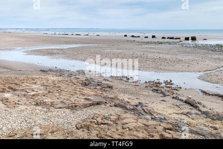 English shoreline along rocky coast and sandy beach on sunny morning in summer with view of sea under blue sky, Fraisthorpe, Yorkshire, UK. Stock Photo