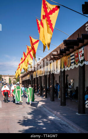 Priests walking in front of Palace of the Governors festooned with flags and coats of arms, Fiesta de Santa Fe, Santa Fe, New Mexico USA Stock Photo