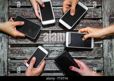 Top view of a group of teenagers people using mobile phone together - mobile internet messaging phone addiction - new generation youths spending time Stock Photo