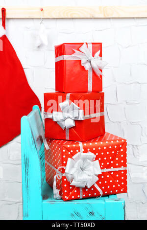 Christmas presents on blue chair on brick wall background Stock Photo