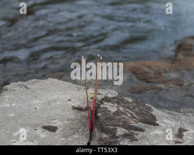 Incense sticks in stone on the banks of the river. Selective focus. Stock Photo