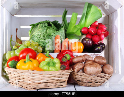 Vegetables in crate and in baskets on white wooden box background Stock Photo