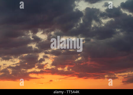 A cloudy sky at sunset time, with different shades of gray and orange Stock Photo