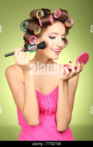 Beautiful girl in hair curlers on green background Stock Photo