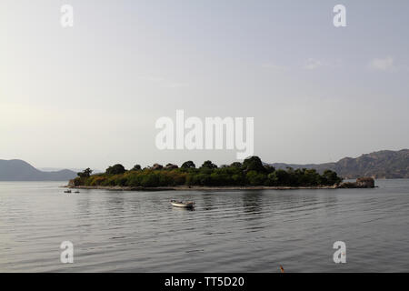 lonely fishing boat docked in calm lake. wooden fishing boat in a still lake water. image of wooden fishing boat moored on the shore. space for text. Stock Photo