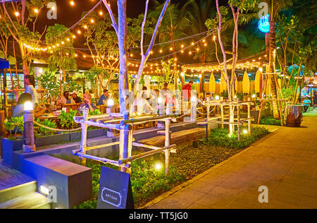 AO NANG, THAILAND - APRIL 27, 2019: The evening walk along the main promenade with a view on crowded outdoor retaurant, decorated with lighting garlan Stock Photo