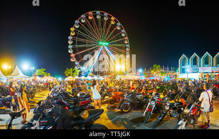 AO NANG, THAILAND - APRIL 27, 2019: The view on hundreds of parked motorcycles of Ao Nang Bike Week participants; ferris wheel and night market stalls Stock Photo