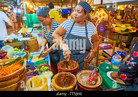 AO NANG, THAILAND - APRIL 27, 2019: Street food vendor makes traditional spicy salad, mixing vegetables and fruits with mortar and pestel in stall of Stock Photo