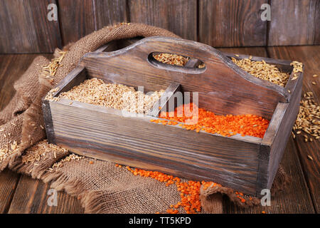 Groats in wooden box on sackcloth napkin on wooden floor on wooden wall background Stock Photo
