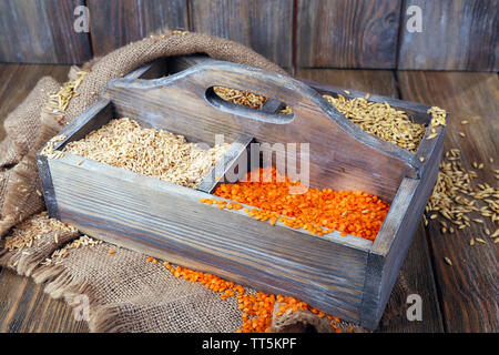 Groats in wooden box on sackcloth napkin on wooden floor on wooden wall background Stock Photo