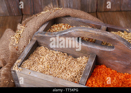 Groats in wooden box on sackcloth napkin on wooden floor on wooden wall background Stock Photo