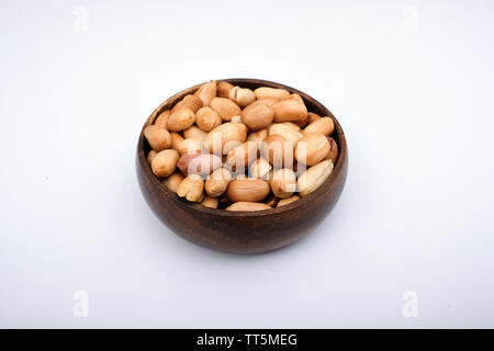 Roasted peanuts in bowl with isolated white surface Stock Photo