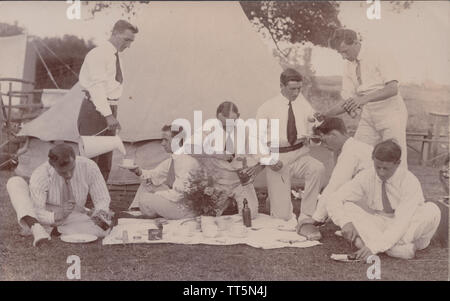 Vintage Early 20th Century Photographic Postcard of Smartly Dressed Men Having a Picnic in Front of a Tent (Camp Site). Stock Photo
