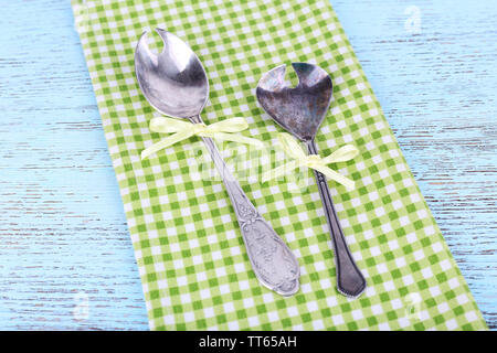 Metal spoons on green checkered napkin on wooden background Stock Photo
