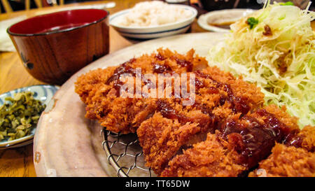 Katsudon, popular Japanese food, a bowl of rice topped with a deep-fried pork cutlet, egg, vegetables, and condiments. Close up. Stock Photo