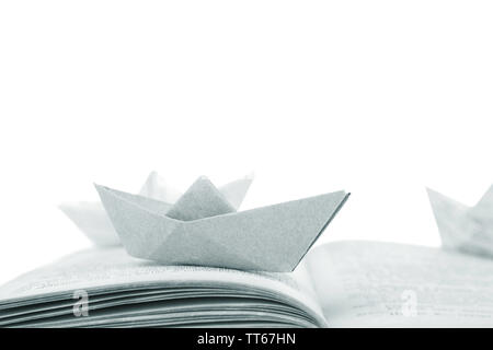 Origami boats on old book, on white background Stock Photo