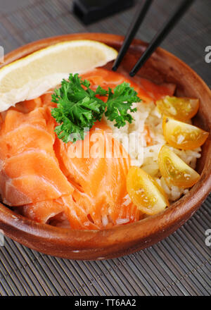 Bowl of boiled rice and fresh salted salmon on bamboo mat background Stock Photo