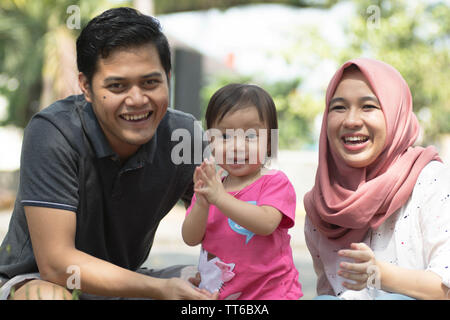 young muslim family with one children playing at park and looking to the camera in sunny day Stock Photo