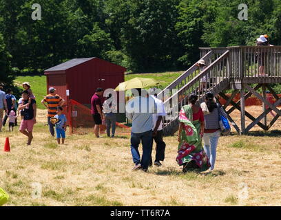 Middlefield, CT USA. Jun 2019. An Indian American family walking towards a New England fruit orchards to go picking strawberries. Stock Photo