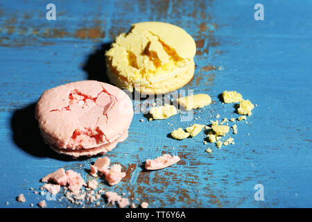 Bright tasty broken macaroons cakes on old wooden background Stock Photo