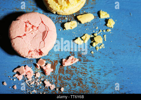 Bright tasty broken macaroons cakes on old wooden background Stock Photo