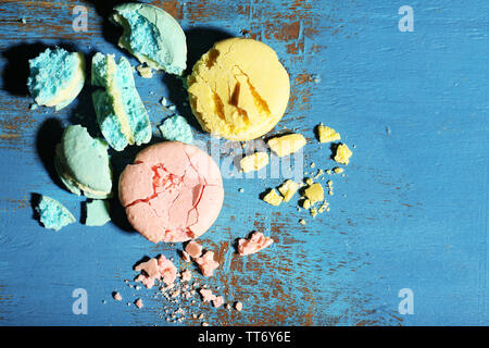 Bright tasty broken macaroons cakes on old wooden background Stock Photo