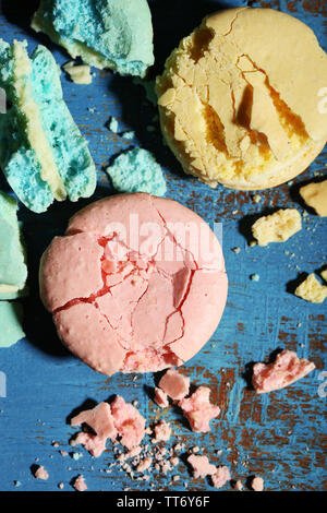 Bright tasty broken macaroons cakes on old wooden background Stock Photo